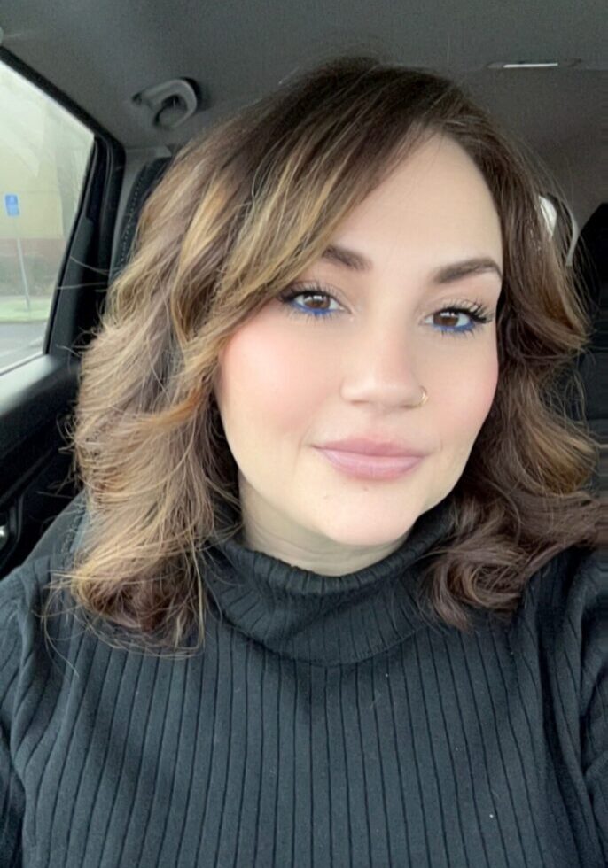 Smiling woman with curled brown hair in car